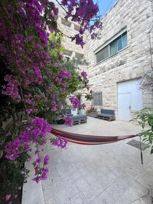 a hammock in front of a building with purple flowers at Locations Amman Palm Tree 4 in Ash Shumaysānī