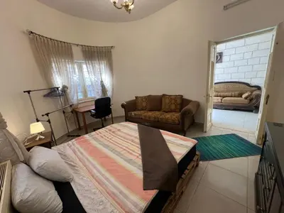 a living room with a bed and a couch at Locations Amman Palm Tree 4 in Ash Shumaysānī