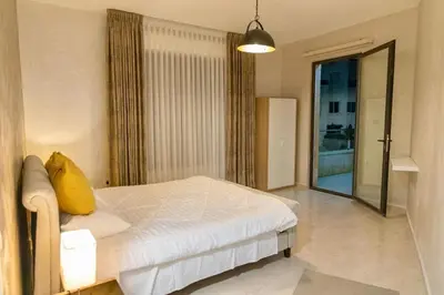 a bedroom with a white bed with a yellow pillow on it at High-end Apartment 2BDR in The most lively AMMAN شقة فاخرة في الدوار السابع in Amman