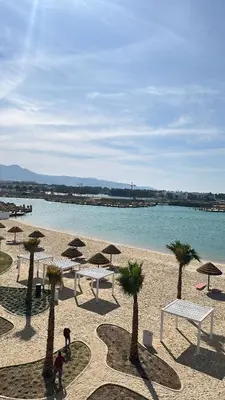 a group of tables and umbrellas on a beach at Azure haven Ayla Sea view Apartment in Aqaba