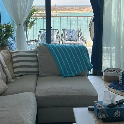 a living room with a couch with a view of the ocean at Azure haven Ayla Sea view Apartment in Aqaba