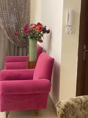 a pink chair with a vase of flowers in a room at Family Spacious newly furnished 2 Bedroom 2 bath in Amman