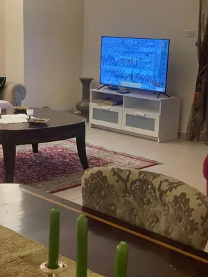 a living room with a tv and a couch and a table at Family Spacious newly furnished 2 Bedroom 2 bath in Amman