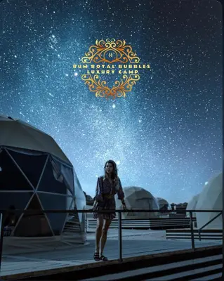 a woman standing in front of tents in the stars at RUM ROYAL BUBBlES LUXURY CAMP in Wadi Rum