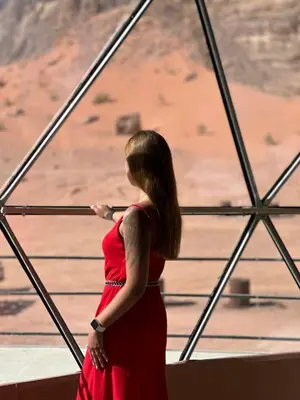 a woman in a red dress looking at the desert at RUM ROYAL BUBBlES LUXURY CAMP in Wadi Rum