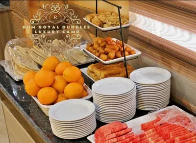 a buffet with plates of fruit and other food at RUM ROYAL BUBBlES LUXURY CAMP in Wadi Rum