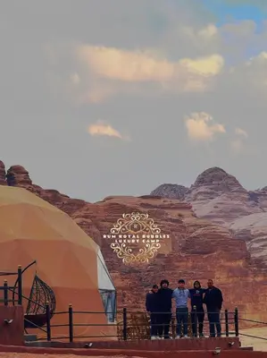 a group of people standing in front of a mural at RUM ROYAL BUBBlES LUXURY CAMP in Wadi Rum
