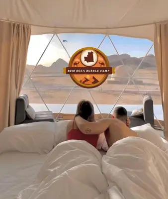 a man and a woman laying in bed in a tent at RUM ROZA BUBBLES lUXURY CAMP in Wadi Rum