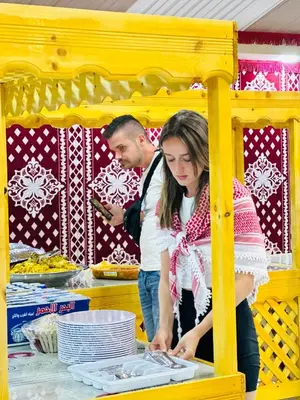 a man and a woman looking at plates on a table at WADI RUM STAR LOTE LUXURY CAMp & BUBBLES ROOM in Wadi Rum