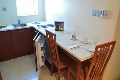 a kitchen with a table with two chairs and a sink at فندق أميري سويت in Umm Uthainah