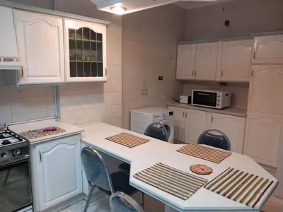 a kitchen with white cabinets and a table and chairs at Abdoun apartment with a garden in Amman