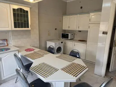 a kitchen with a table and chairs and a microwave at Abdoun apartment with a garden in Amman