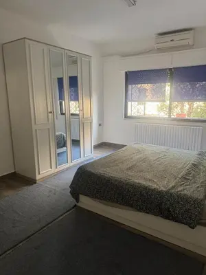 a bedroom with a bed and a large window at Abdoun apartment with a garden in Amman