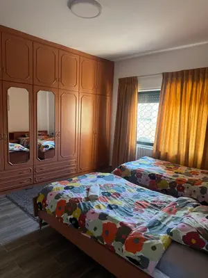 a bedroom with two beds and wooden cabinets at Abdoun apartment with a garden in Amman