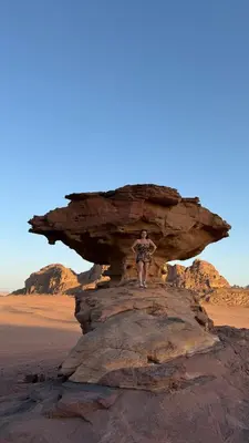 a man standing on a rock in the desert at Wadi Rum famous luxury camp in Wadi Rum