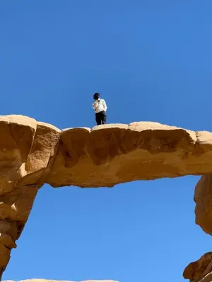 a man standing on top of a rock formation at Wadi Rum famous luxury camp in Wadi Rum