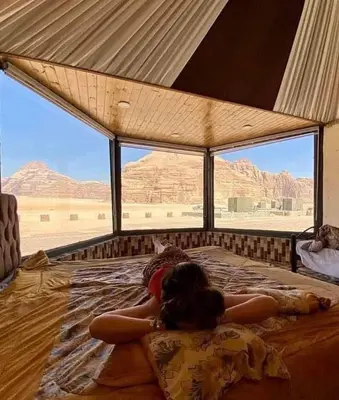 a woman laying on a bed in the desert at Sami Rum Mountains in Wadi Rum