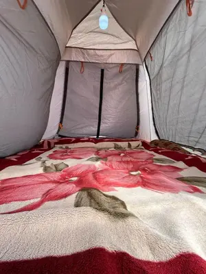 a bed in a tent with a blanket on it at Wadi Rum Paris Cave in Wadi Rum