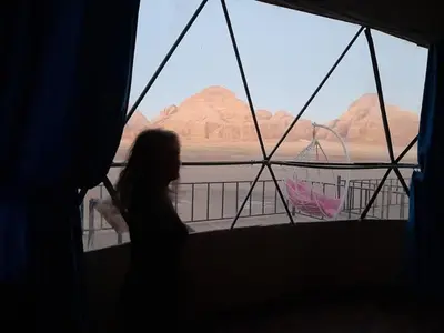 a woman looking out of a window at the desert at Wadi Rum murahf camp in Wadi Rum