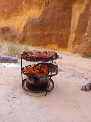 a grill with two trays of food in the desert at Wadi Rum murahf camp in Wadi Rum