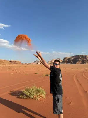 a man standing in the desert throwing a frisbee at Wadi Rum murahf camp in Wadi Rum