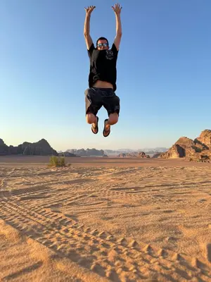 a man jumping in the air in the desert at Wadi Rum murahf camp in Wadi Rum
