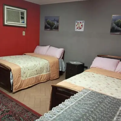 a bedroom with two beds and a red wall at Noplity bed and breakfast in Al Qunayţirah