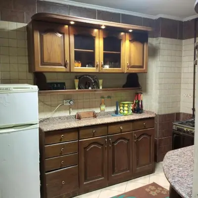 a kitchen with wooden cabinets and a white refrigerator at Noplity bed and breakfast in Al Qunayţirah