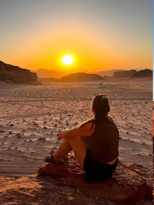 a woman sitting on a rock watching the sunset at RUM DESERT BREEZE lUXURY CAMP&JEEP TOUR in Wadi Rum