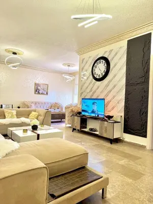 a living room with a tv and a clock on the wall at Stylish 3 Bedroom apartment in Amman in Amman