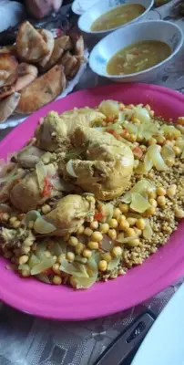 a pink plate of food with corn and chicken and vegetables at بيت راس هوستل in Bayt Raʼs