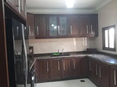 a kitchen with wooden cabinets and a sink at بيت راس هوستل in Bayt Raʼs
