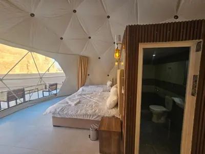 a bedroom with a bed with a large umbrella at Lowrance luxury camp in Wadi Rum