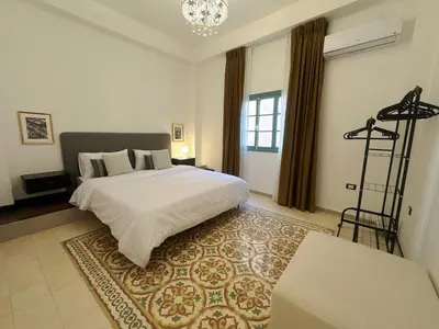 a bedroom with a large white bed and a chandelier at Old Town Charming Two-Bedroom Flat in Amman