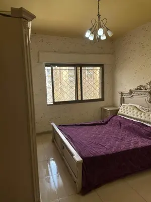 a bedroom with a bed with purple sheets and a window at شقه مفروشه in Amman