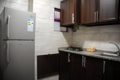 a kitchen with a white refrigerator and wooden cabinets at ساكب هاوس in Sākib