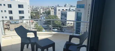 a balcony with two chairs and a view of a city at العبد للشقق الفندقية in Amman