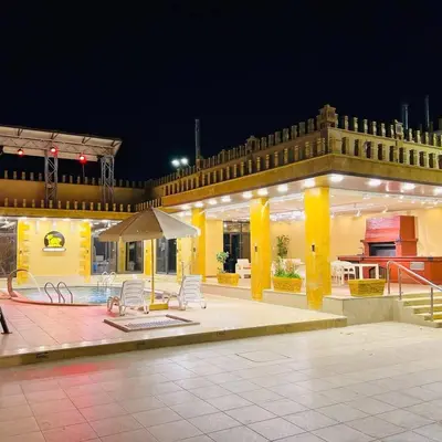 a large building with a patio with chairs and a umbrella at Kareem celebrations Hall صاله افراح in Irbid