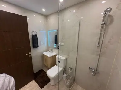 a bathroom with a toilet and a glass shower at Third circle Luxury Hotel apartment New in Amman