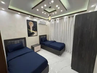 a bedroom with two beds with blue sheets in it at Third circle Luxury Hotel apartment New in Amman