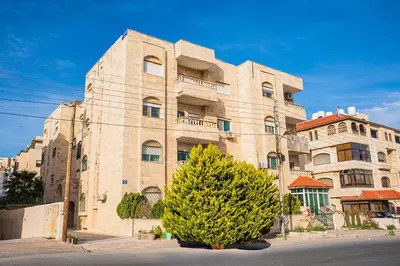 a large stone building with a tree in front of it at 3 Bedrooms Cozy Apartment Prime Location Walk Anywhere شقة مفروشة واسعة شارع الجاردنز in Amman