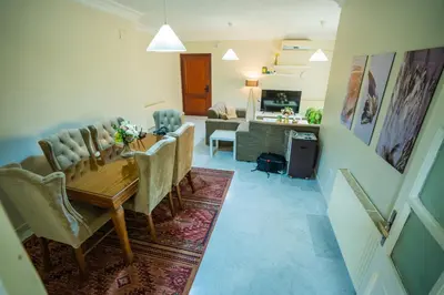 a dining room with a table and chairs and a living room at 3 Bedrooms Cozy Apartment Prime Location Walk Anywhere شقة مفروشة واسعة شارع الجاردنز in Amman