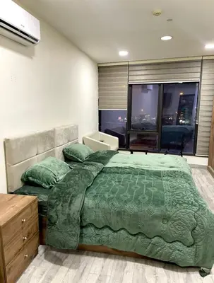 a bedroom with a bed with a green comforter at Falcon Real Estate in Amman