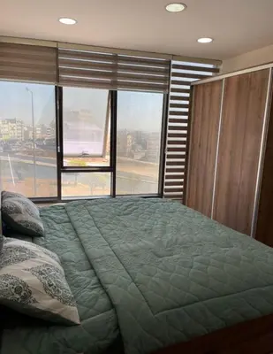 a bedroom with a large bed with a large window at Falcon Real Estate in Amman