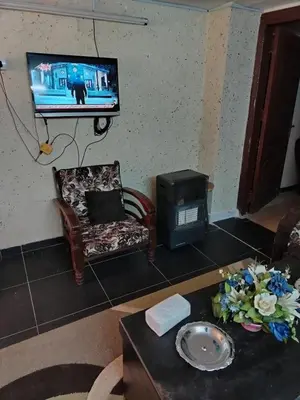 a living room with a tv and a chair and a table at شقة الراحة والسعادة economic comfortable flat first floor in Amman