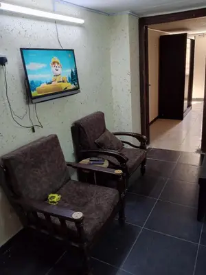 a living room with two chairs and a tv on the wall at شقة الراحة والسعادة economic comfortable flat first floor in Amman