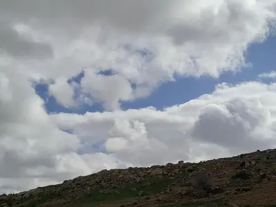 a cloudy sky above a hill with a mountain at Dana Valley Tourism Hotel in Dana