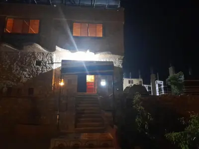 a building with a red door and stairs at night at Dana Valley Tourism Hotel in Dana