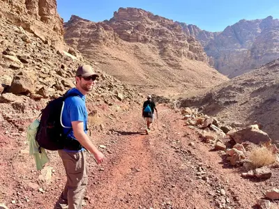 two people walking down a dirt road in the desert at Dana Valley Tourism Hotel in Dana