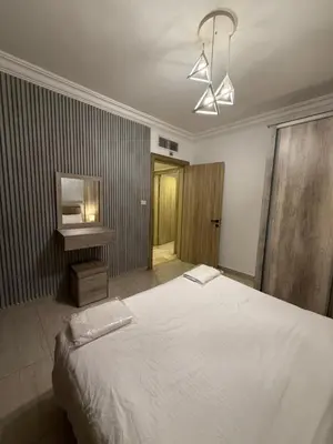 a bedroom with a large white bed and a table at unique 2bedroom at abdoun 007 in Amman